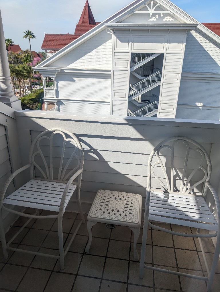 Two chairs and a small side table on a private balcony outside The Villas at Grand Floridian Resort Studio Villa room