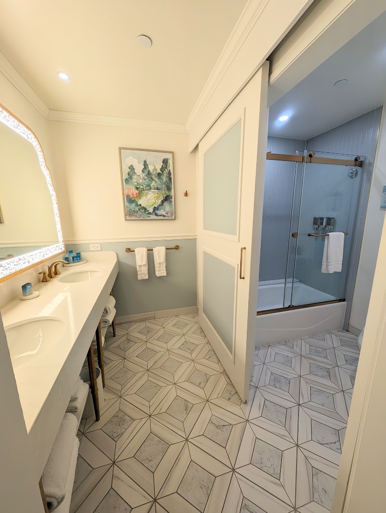 Ornate tile floors, a gorgeous back-lit mirror, and blue-gray tiles make for a pretty Grand Floridian Resort Studio Villa bathroom