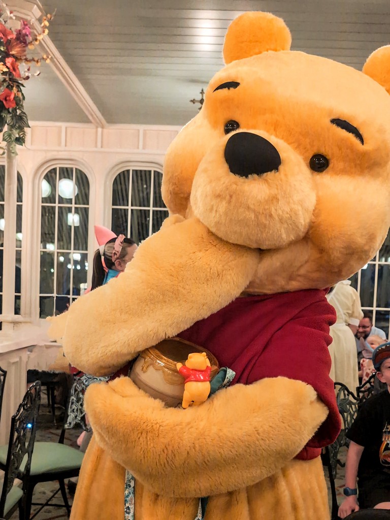 Winnie the Pooh pretends to eat honey from a Winnie the Pooh inspired Disneyland Tokyo popcorn bucket