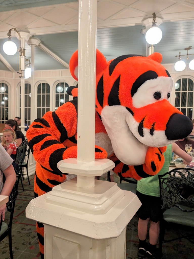 Tigger bounds over and peeks out from behind a post surprising guests at The Crystal Palace